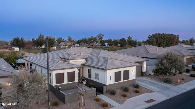 view of front of property featuring concrete driveway, a tiled roof, an attached garage, fence, and stucco siding