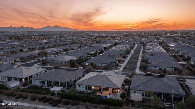 aerial view at dusk featuring a mountain view and a residential view