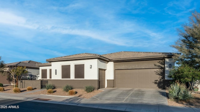 prairie-style home featuring a garage, concrete driveway, and stucco siding