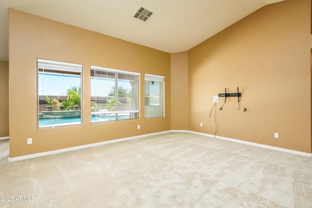 carpeted spare room with visible vents, vaulted ceiling, and baseboards