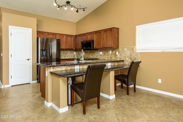 kitchen featuring dark stone counters, a sink, appliances with stainless steel finishes, and decorative backsplash