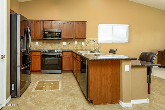 kitchen featuring appliances with stainless steel finishes, decorative backsplash, lofted ceiling, and a sink