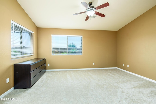empty room with a ceiling fan, a wealth of natural light, and light carpet