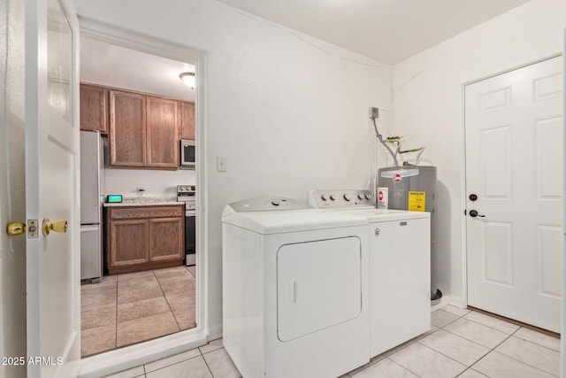 clothes washing area with light tile patterned floors, independent washer and dryer, and electric water heater