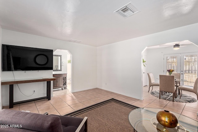 tiled living room with french doors and ceiling fan