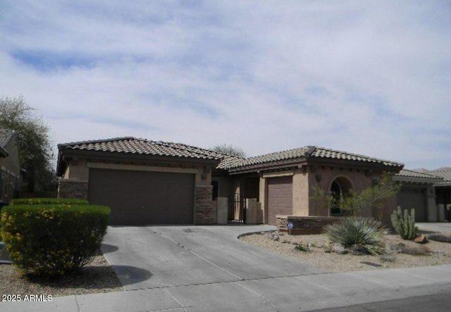 view of front facade featuring an attached garage, a tiled roof, concrete driveway, and stucco siding