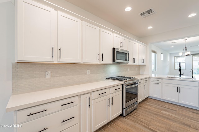 kitchen with light hardwood / wood-style flooring, sink, stainless steel appliances, and white cabinetry