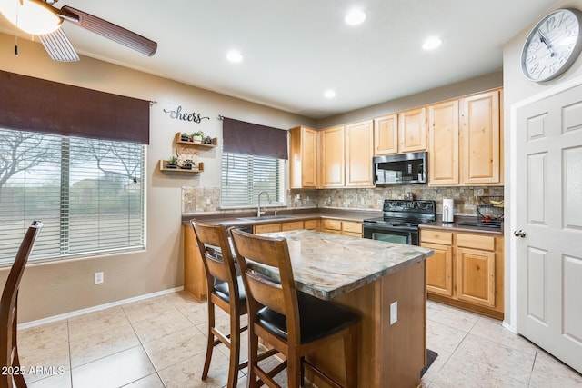 kitchen featuring light brown cabinets, a sink, black electric range oven, tasteful backsplash, and stainless steel microwave