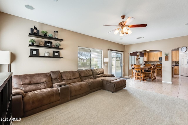 living room with light tile patterned floors, visible vents, light carpet, ceiling fan, and baseboards