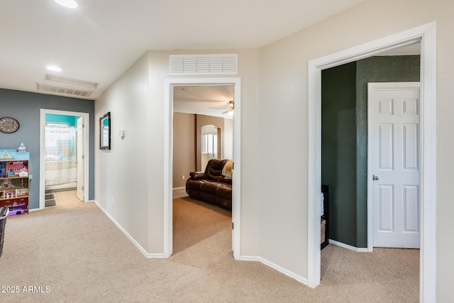 hall featuring light carpet, baseboards, and visible vents