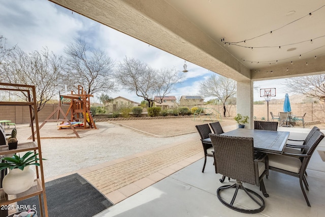 view of patio featuring outdoor dining space, a playground, and fence