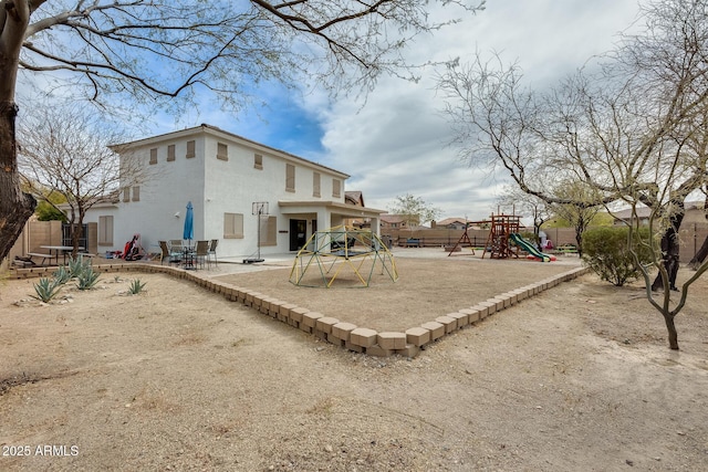 back of property with a patio area, a playground, fence, and stucco siding