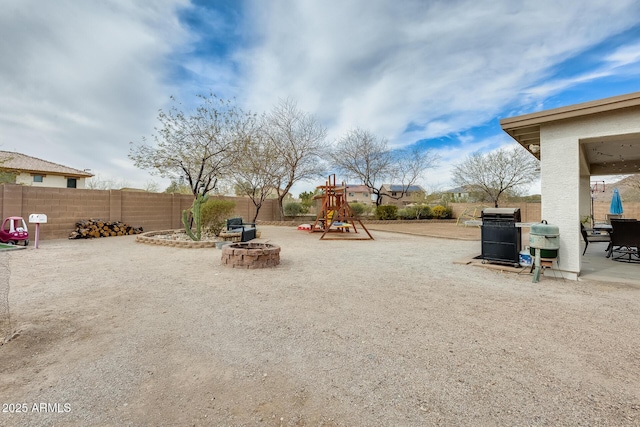 view of yard with a fire pit, a patio, playground community, and fence