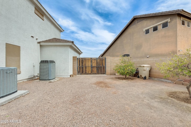 exterior space with central AC unit, fence, and stucco siding