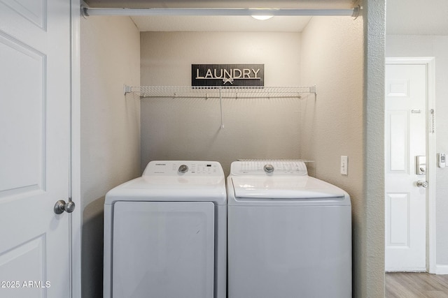 laundry area featuring washer and clothes dryer, laundry area, and wood finished floors