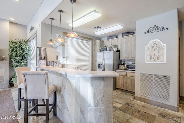 kitchen with light countertops, appliances with stainless steel finishes, a breakfast bar, and visible vents