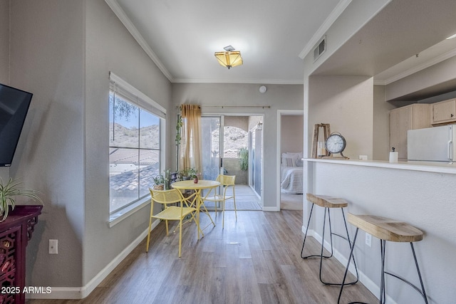dining space featuring visible vents, crown molding, baseboards, and light wood-type flooring