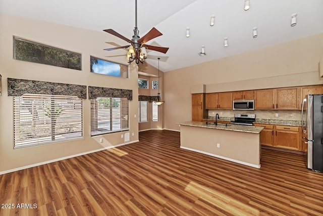 kitchen featuring appliances with stainless steel finishes, brown cabinets, open floor plan, dark wood-style flooring, and high vaulted ceiling