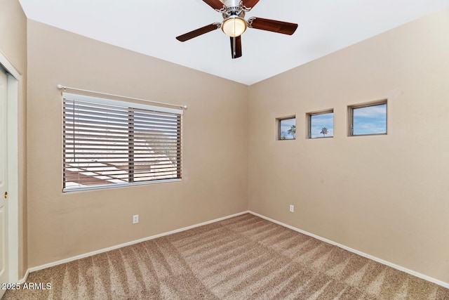 spare room featuring carpet, baseboards, and ceiling fan