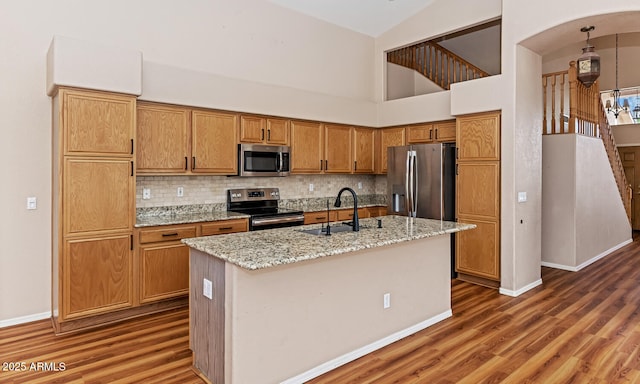 kitchen with stainless steel appliances, wood finished floors, a sink, and tasteful backsplash