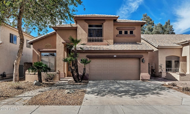 mediterranean / spanish home with a garage, a tile roof, concrete driveway, and stucco siding