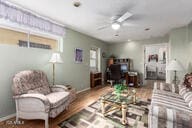 living room featuring baseboards and a ceiling fan