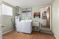 clothes washing area with laundry area, a sink, and wood finished floors