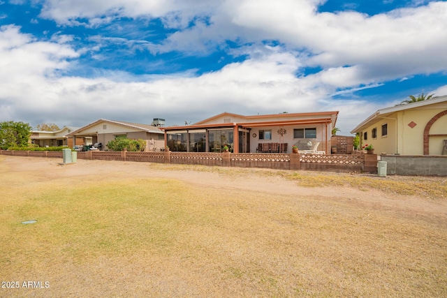 rear view of house featuring a sunroom and a fenced front yard