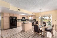 kitchen with fridge, light brown cabinets, a kitchen island, and light tile patterned floors