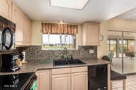 kitchen featuring a skylight, electric range, a sink, black microwave, and backsplash