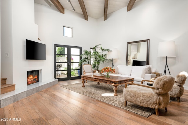 living room with a tiled fireplace, wood ceiling, hardwood / wood-style floors, french doors, and beam ceiling