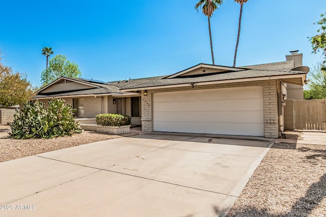 ranch-style home with driveway, brick siding, an attached garage, and fence