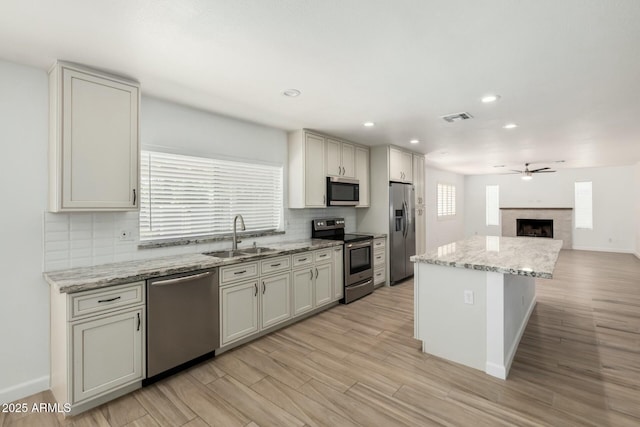 kitchen featuring visible vents, decorative backsplash, appliances with stainless steel finishes, a ceiling fan, and a sink