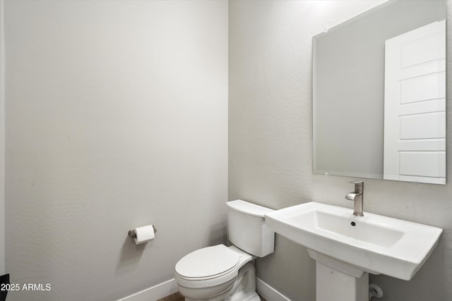 bathroom featuring a sink, toilet, and baseboards