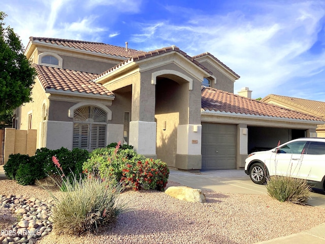 mediterranean / spanish-style house with a garage, stucco siding, concrete driveway, and a tile roof