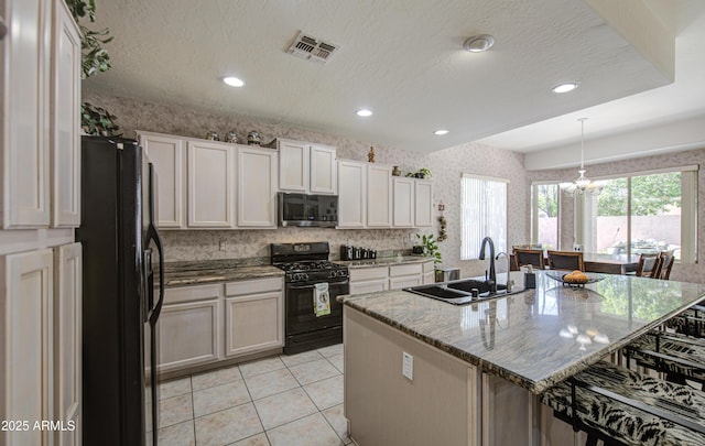 kitchen featuring light stone countertops, a breakfast bar, a sink, wallpapered walls, and black appliances