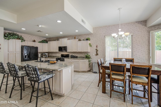 kitchen with visible vents, a sink, black appliances, an inviting chandelier, and wallpapered walls