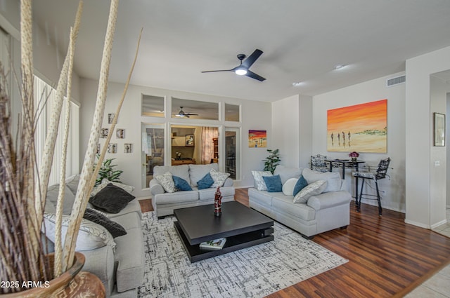 living room featuring visible vents, baseboards, ceiling fan, and wood finished floors