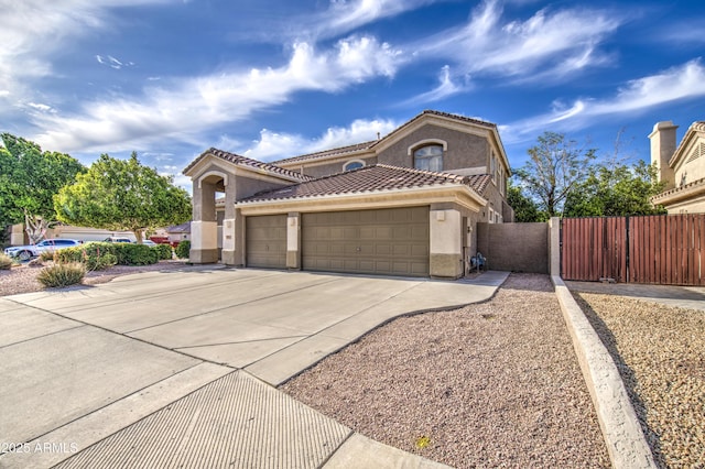 mediterranean / spanish house with fence, an attached garage, stucco siding, a gate, and driveway