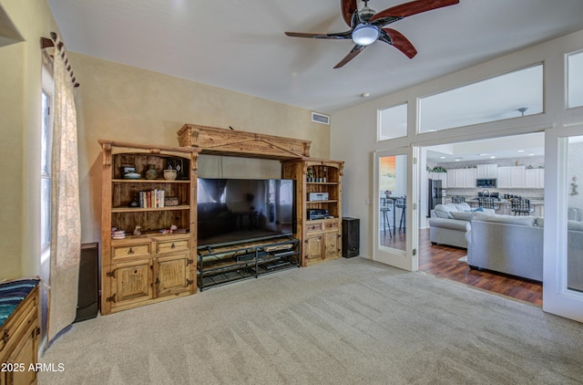 living area featuring carpet floors, a ceiling fan, and visible vents