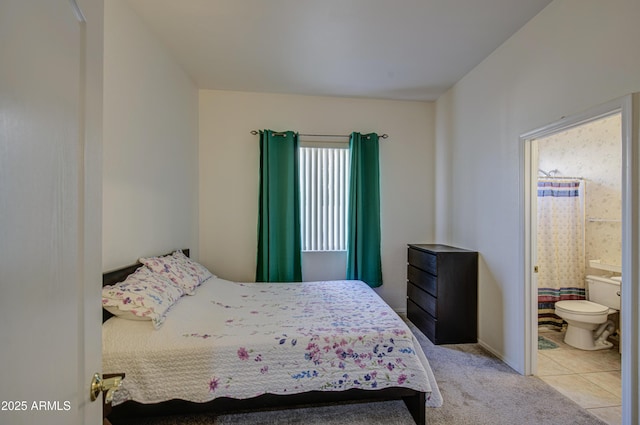 bedroom featuring ensuite bath and light carpet