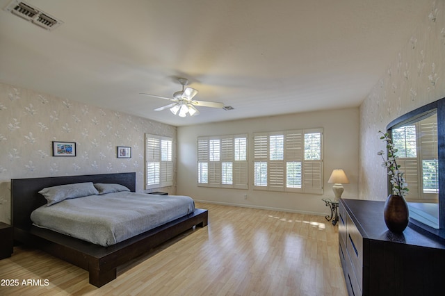 bedroom featuring wallpapered walls, visible vents, multiple windows, and light wood-style flooring