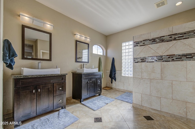 bathroom featuring visible vents, a sink, and two vanities
