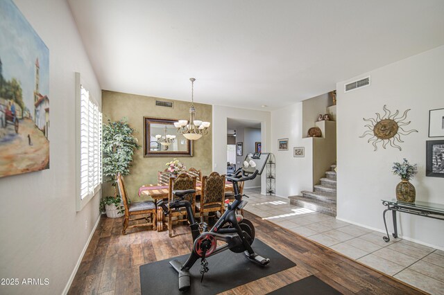 exercise area with baseboards, hardwood / wood-style flooring, a chandelier, and visible vents