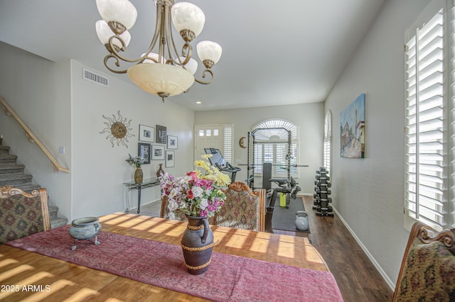 dining area featuring visible vents, an inviting chandelier, dark wood-style flooring, baseboards, and stairway