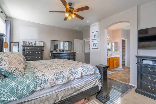 bedroom featuring ceiling fan, sink, light carpet, and ensuite bath