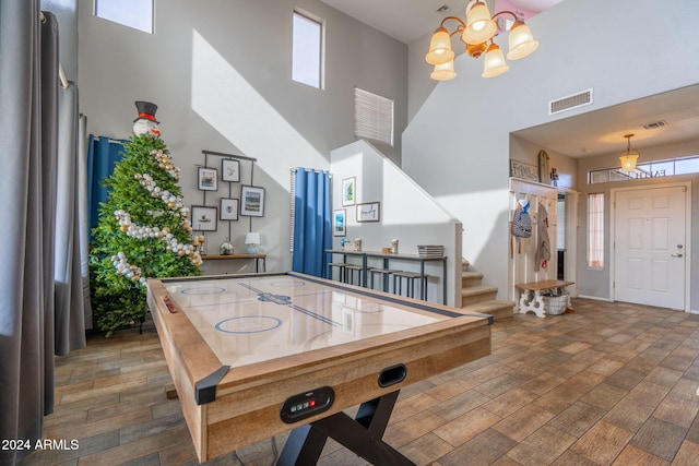 recreation room featuring hardwood / wood-style floors, a wealth of natural light, and a high ceiling