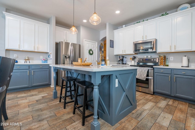 kitchen featuring white cabinetry, hanging light fixtures, and appliances with stainless steel finishes