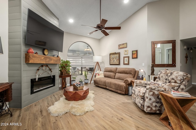 living room featuring ceiling fan, high vaulted ceiling, and light hardwood / wood-style flooring