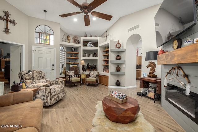 living room with ceiling fan with notable chandelier, high vaulted ceiling, and light hardwood / wood-style flooring